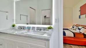 A modern bathroom with a large mirror, two sinks, and a shower.