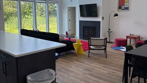 A spacious living area with a large window, a fireplace, and a dining table.