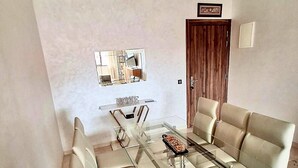 A dining area with a glass-top table and beige upholstered chairs. - Winterized apartment (Marrakesh)