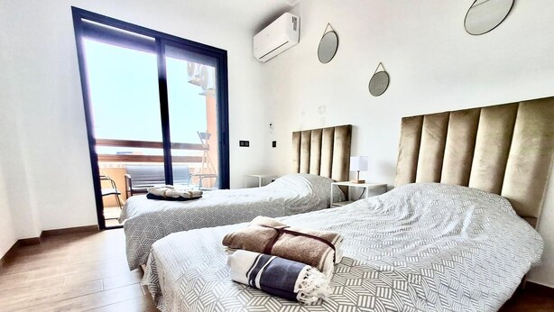 A hotel room with two beds, a balcony, and a modern design. - Winterized apartment (Marrakesh)