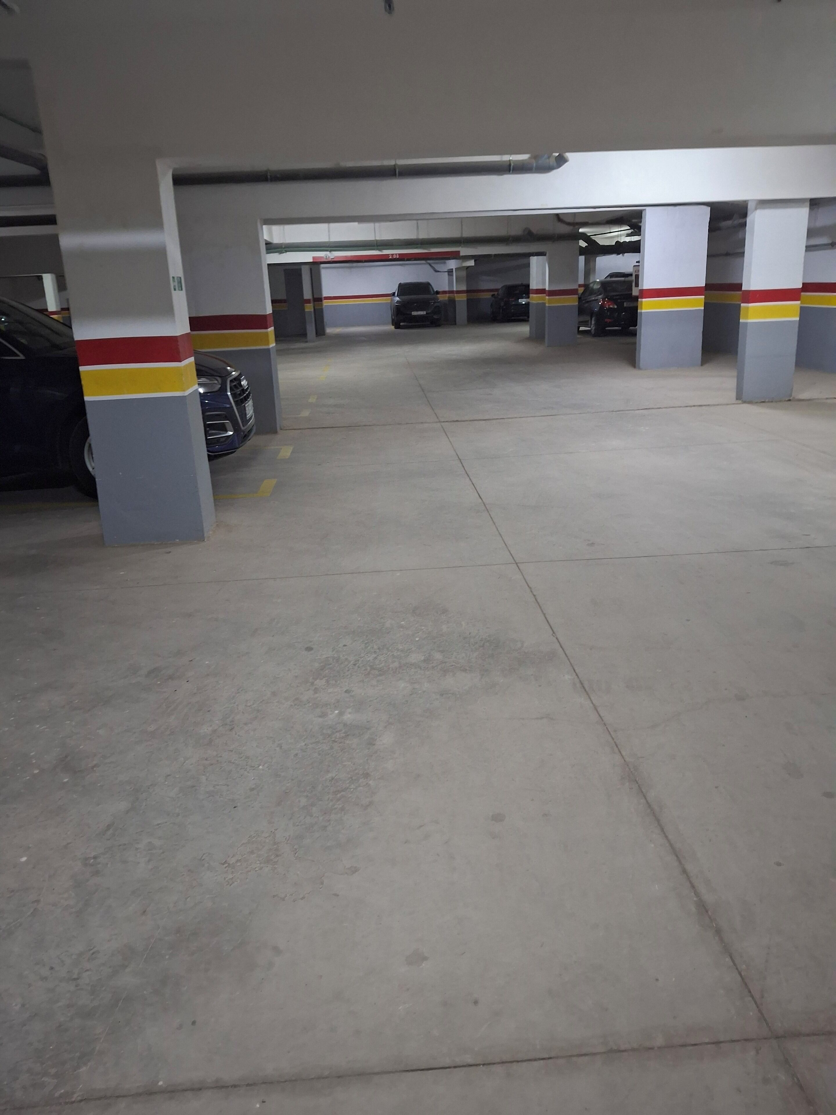 A parking garage with concrete pillars and yellow lines on the floor.