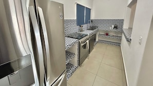 A compact kitchen with a stainless steel refrigerator, a built-in oven, and a sink. - Cancun House in Hotel Zone (Cancún)