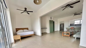 A spacious living area with a bed, a dining table, chairs, and ceiling fans. - Cancun House in Hotel Zone (Cancún)