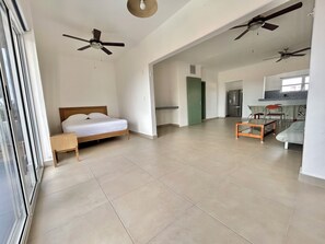A spacious living area with a bed, a dining table, chairs, and ceiling fans.