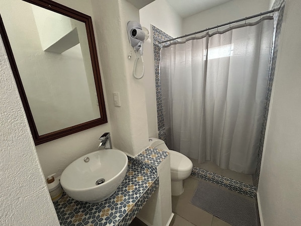 A bathroom with a white sink, a toilet, a shower curtain, and a mirror. - Cancun House in Hotel Zone (Cancún)