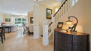 A spacious living area with a staircase, a dining table, and a large chandelier. - Tropical Dreams by the Sea - Vacation Home with Private Pool & Close Proximity to Beach (Destin)