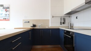 A modern kitchen with dark blue cabinets, a white countertop, and a stainless steel range hood. - APARTMENT LA BOLERA INDOOR BOWLING ALLEY (Llanes)
