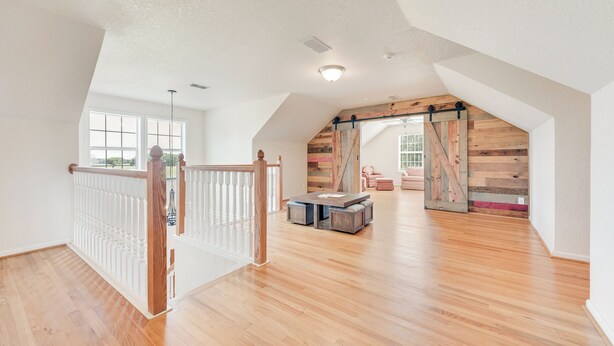 A spacious loft with high ceilings, wooden flooring, a staircase, and a view of the outdoors. - Luxury 90-acre 5BR Ranch near Cedar Creek (Kemp)