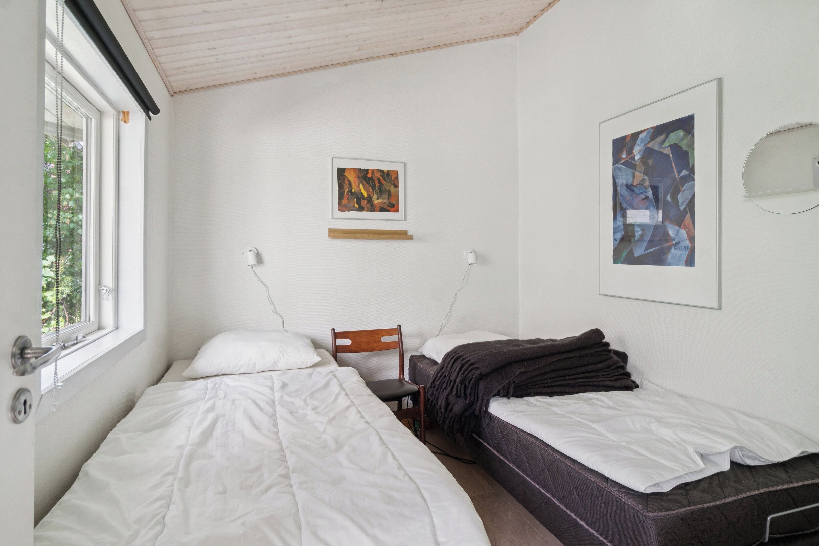 Ein Schlafzimmer mit zwei Betten, einem Sessel, einem Schreibtisch und Bildern an den Wänden.