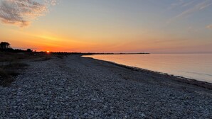 A pebbled beach with a sunset in the background.