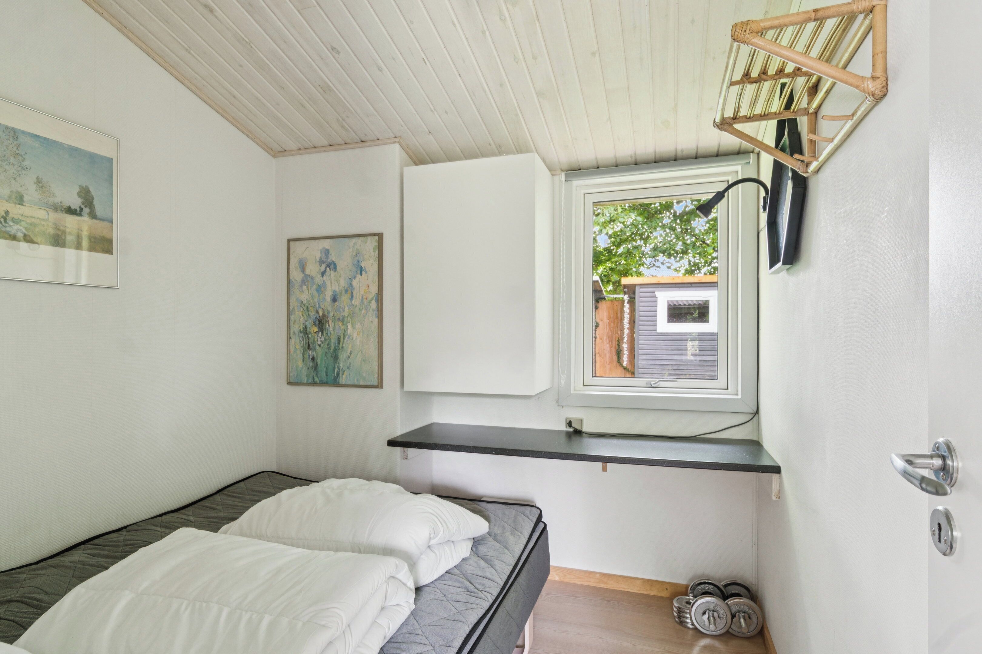 Une chambre à coucher avec un lit, une fenêtre, une étagère et une porte.