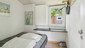 A bedroom with a bed, a window, a shelf, and a door.