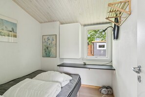 A bedroom with a bed, a window, a shelf, and a door.