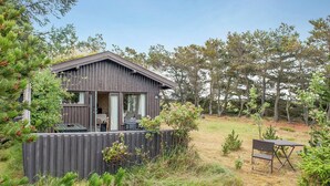 A cabin with a deck, a dining area, and a small outdoor seating space. - Lovely cottage close to the North Sea (Pandrup)