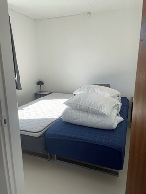 A bedroom with a bed, pillows, a nightstand, and a lamp. - True summer charm by beach and dunes (Nexø)