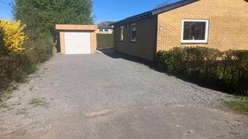 Une allée de gravier mène à un bâtiment en briques doté d’une porte de garage et d’une fenêtre.