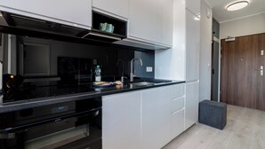 Una cocina moderna con encimera negra, armarios blancos y horno integrado.