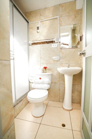 Une salle de bain comprenant des toilettes, un lavabo et un espace douche.