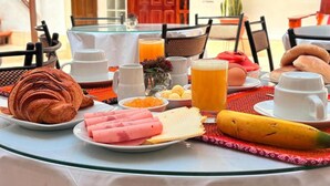 A breakfast table with croissants, ham, cheese, a banana, and a glass of orange juice. - Hotel Horizonte Cuzco (Cusco)