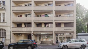 Een meerlaags gebouw met een platte gevel, meerdere balkons en een gelijkvloerse ingang met borden.