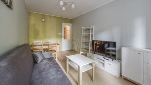 Een moderne woonkamer met een grijze bank, een witte salontafel, een televisie en een witte kast.