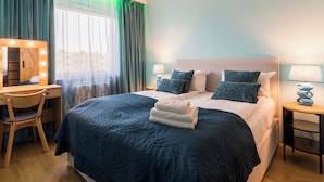 Une chambre d’hôtel comprenant un lit, une coiffeuse avec éclairage, un bureau et une chaise.