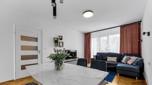Ein modernes Wohnzimmer mit einem weißen Marmorestisch, einer Couch und einem Fernseher.