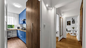 Eine moderne Küche mit blauen Schränken, einer Holztür und Blick zum Essbereich.