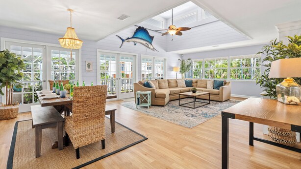 A spacious living room with a high ceiling, a ceiling fan, and a large window overlooking greenery. - Salty Sailfish | Private Pool + Hot Tub + Siesta Key (Sarasota)