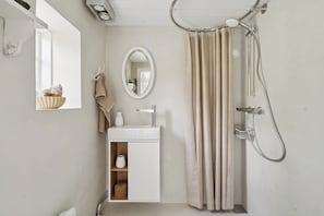 Une salle de bain Ă©quipĂ©e dâune douche, dâun lavabo, dâun miroir et dâun porte-serviettes.