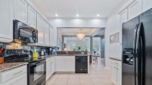 A modern kitchen with white cabinets, a black refrigerator, and a granite countertop. - Embrace Luxury: Your Perfect Escape, Orlando Villa 1000 (Kissimmee)