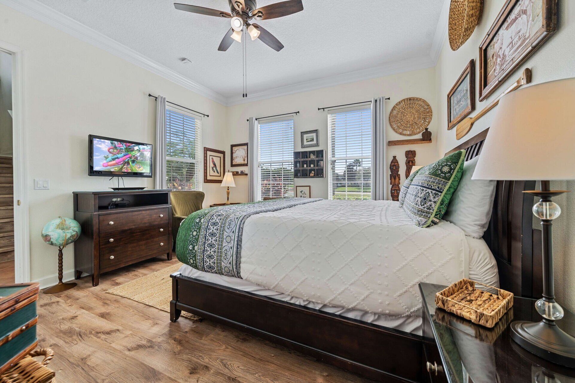 A bedroom with a bed, a ceiling fan, a TV, and a dresser.