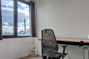 Una habitación con ventana, una silla, un escritorio y un calefactor.