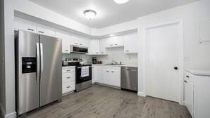 A modern kitchen with white cabinetry, stainless steel appliances, and a wooden floor. - 3-bedroom house in delightful Dayton with WiFi, AC (Dayton)