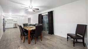 A dining area with a wooden table and chairs, a ceiling fan, and a kitchen in the background. - 3-bedroom house in delightful Dayton with WiFi, AC (Dayton)