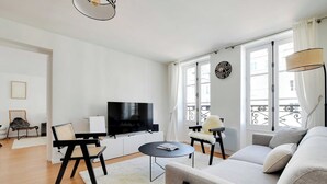 A modern living room with a flat-screen TV, a sofa, a coffee table, and a chair.