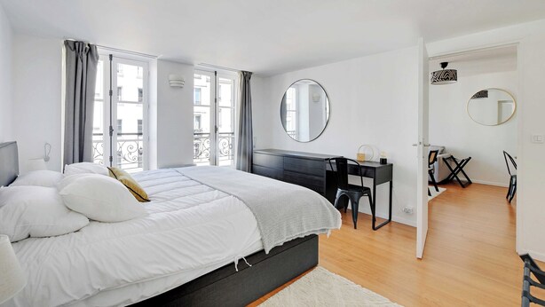 A modern bedroom with a large bed, a desk, and a chair.