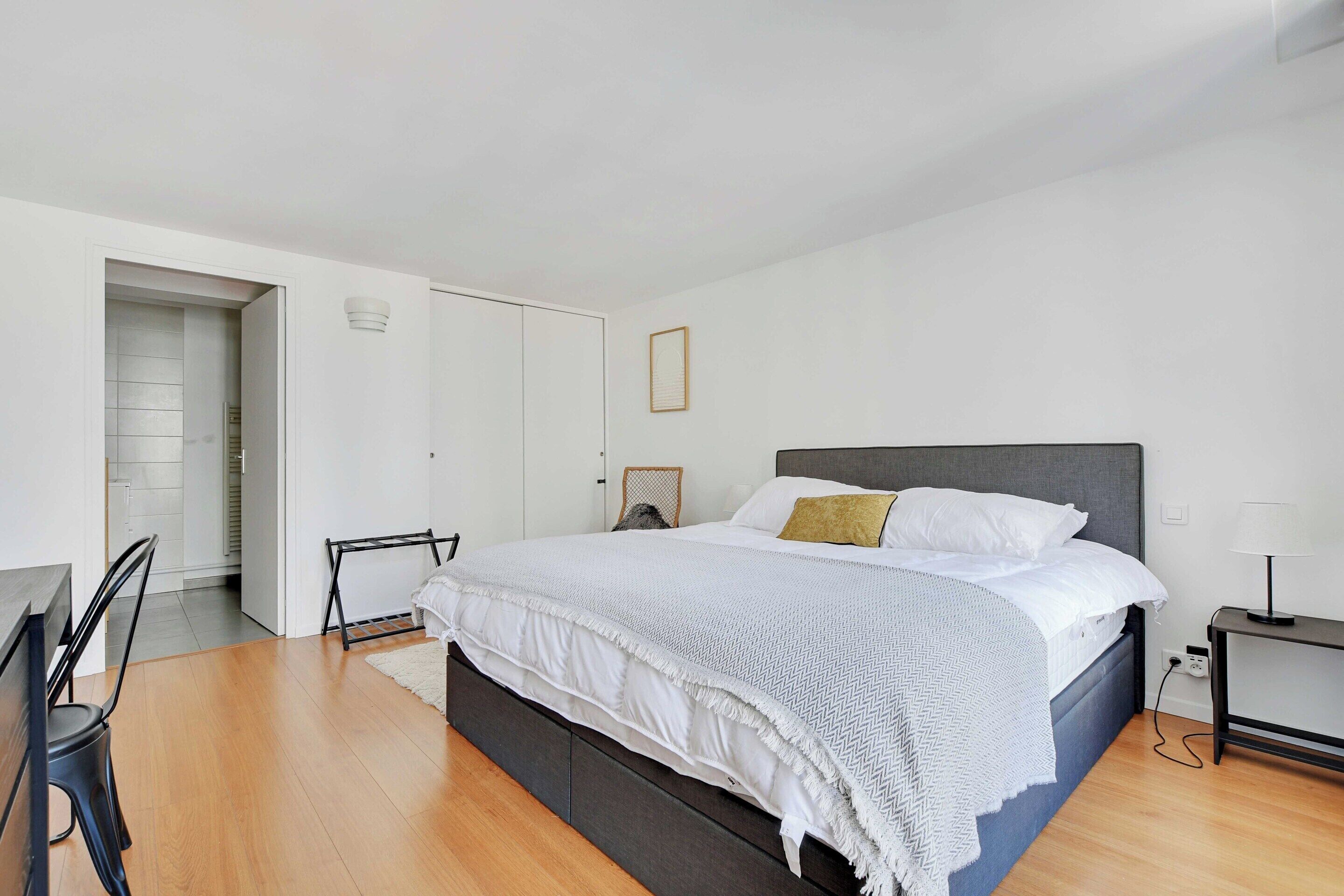 A modern bedroom with a large bed, a desk, and a chair.
