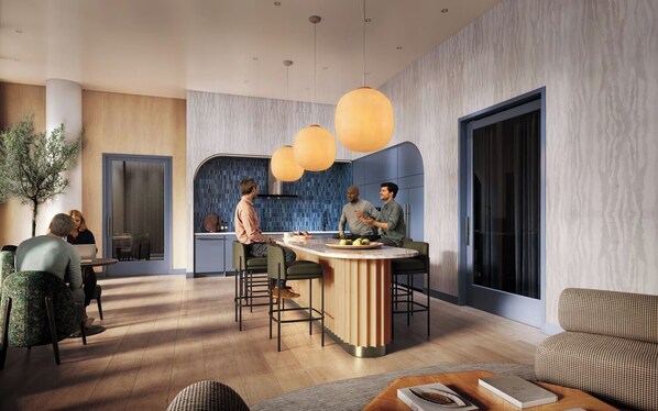 A modern kitchen with a central island, pendant lighting, and a seating area with a view of the city.