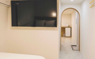 Une chambre d’hôtel équipée d’un lit, d’un téléviseur à écran plat fixé au mur, d’un four à micro-ondes et d’un réfrigérateur dans le coin cuisine.
