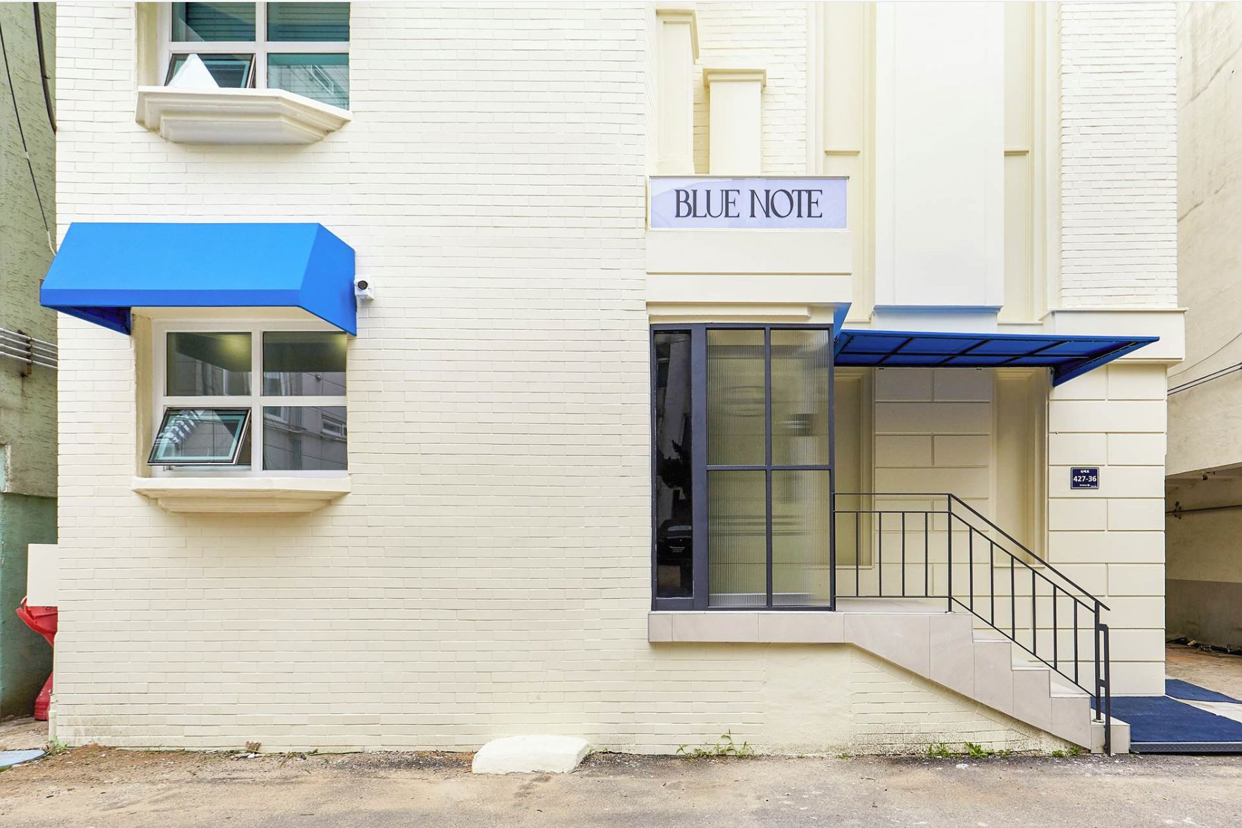 Un edificio con un cartello che riporta la scritta "BLUE NOTE" e un tendone blu sopra l'ingresso.
