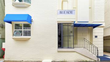 Un edificio con un cartello che riporta la scritta "BLUE NOTE" e un tendone blu sopra l'ingresso.