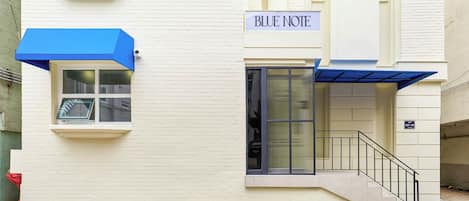 Un bâtiment sur lequel on peut lire l’inscription « BLUE NOTE » et qui est surmonté d’un auvent bleu au-dessus de l’entrée.