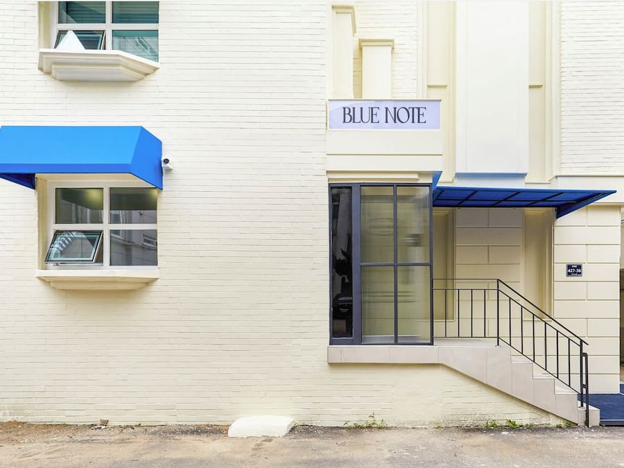 Un edificio con un cartello che riporta la scritta "BLUE NOTE" e un tendone blu sopra l'ingresso.