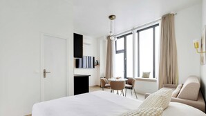 Quarto de hotel com uma cama grande, uma escrivaninha, uma cadeira, uma mesa redonda e um sofá.