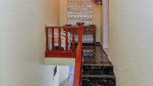 Un escalier avec une rampe en bois, des marches en marbre noir et un mur décoratif orné d’un motif.