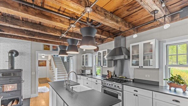 A modern kitchen with a central island, stainless steel appliances, and a rustic wooden ceiling.