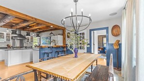 A spacious kitchen with a wooden table, bar stools, and a chandelier.