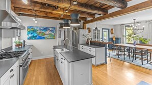 A modern kitchen with a central island, stainless steel appliances, and a rustic wooden ceiling.
