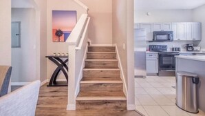 A modern kitchen with white cabinets, a microwave, and a stove. - Waterpark villa near Disney (Davenport)